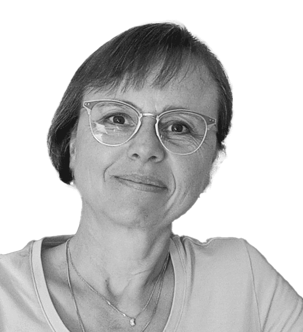 Porträt einer lächelnden Frau mit kurzen Haaren und Brille vor weißem Hintergrund.