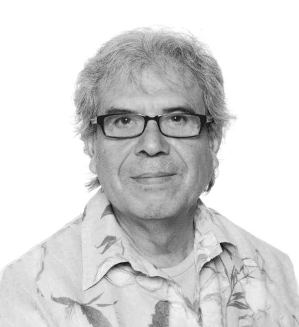 Porträt eines älteren Mannes mit grauen Haaren, Brille und einem gemusterten Hemd vor weißem Hintergrund.